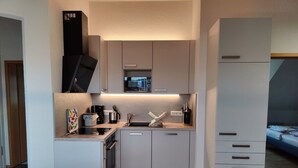 Een kleine keuken met een magnetron, koffiezetapparaat en spoelbak.