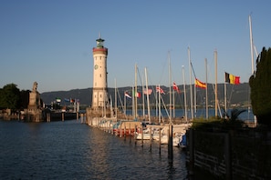 A lighthouse, a dock with boats, and flags. - Apartment 'Panoramablick' with Lake View, Shared Terrace and Wi-Fi (Lindau am Bodensee)