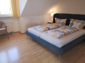 A bedroom with a bed, a chair, a lamp, and a window. - Apartment 'Panoramablick' with Lake View, Shared Terrace and Wi-Fi (Lindau am Bodensee)