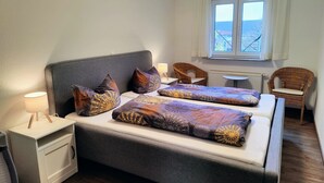 A bedroom with a bed, bedside tables, a window, and two wicker chairs. - Apartment '1' with Shared Terrace, Shared Garden and Wi-Fi (Lindau am Bodensee)