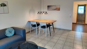 A modern living room with a wooden dining table, two chairs, a sofa, and a coffee table. - Apartment '1' with Shared Terrace, Shared Garden and Wi-Fi (Lindau am Bodensee)