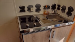 A kitchen with a stove, sink, and wooden cabinets. - Holiday Apartment '19sqm' with Wi-Fi in Quiet St. Georgen Backyard (Freiburg)