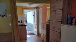 A hallway with wooden cabinets, a kitchen area, and a view to an outdoor balcony. - Holiday Apartment '19sqm' with Wi-Fi in Quiet St. Georgen Backyard (Freiburg)
