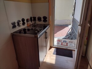 Une cuisine équipée d’une cuisinière, d’un évier et offrant une vue sur la rue.