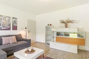 A modern living room with a grey sofa, white coffee table, and a white cabinet with glass doors. - Apartment 'Rastplatz' with Mountain View, Private Terrace and Wi-Fi (Schmallenberg)