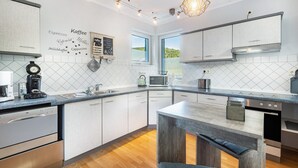 Una cocina moderna con armarios blancos, microondas integrado y una zona para café.