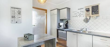 A modern kitchen with a wooden table, a coffee machine, and a chalkboard menu.