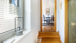 Una escalera conduce a un comedor con vista al cielo a través de una ventana con persianas.