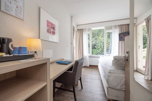 Relax in a stylish room with a comfortable bed, desk, and wall-mounted TV, offering a view of the surrounding greenery.