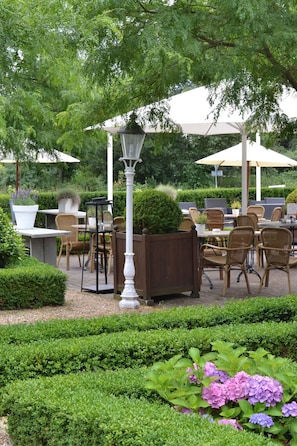 Relax in a serene outdoor seating area surrounded by lush greenery and beautifully maintained gardens.