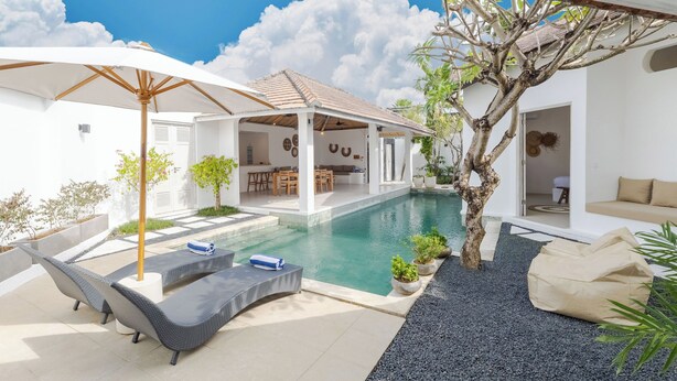 A poolside area with lounge chairs, a covered seating area, and a dining space. - Villa Cocodrilos 2 by Pertama Stay (Seminyak)