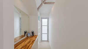 A hallway with a wooden countertop, a large mirror, and a view of a door leading to a bright room. - Villa Cocodrilos 2 by Pertama Stay (Seminyak)