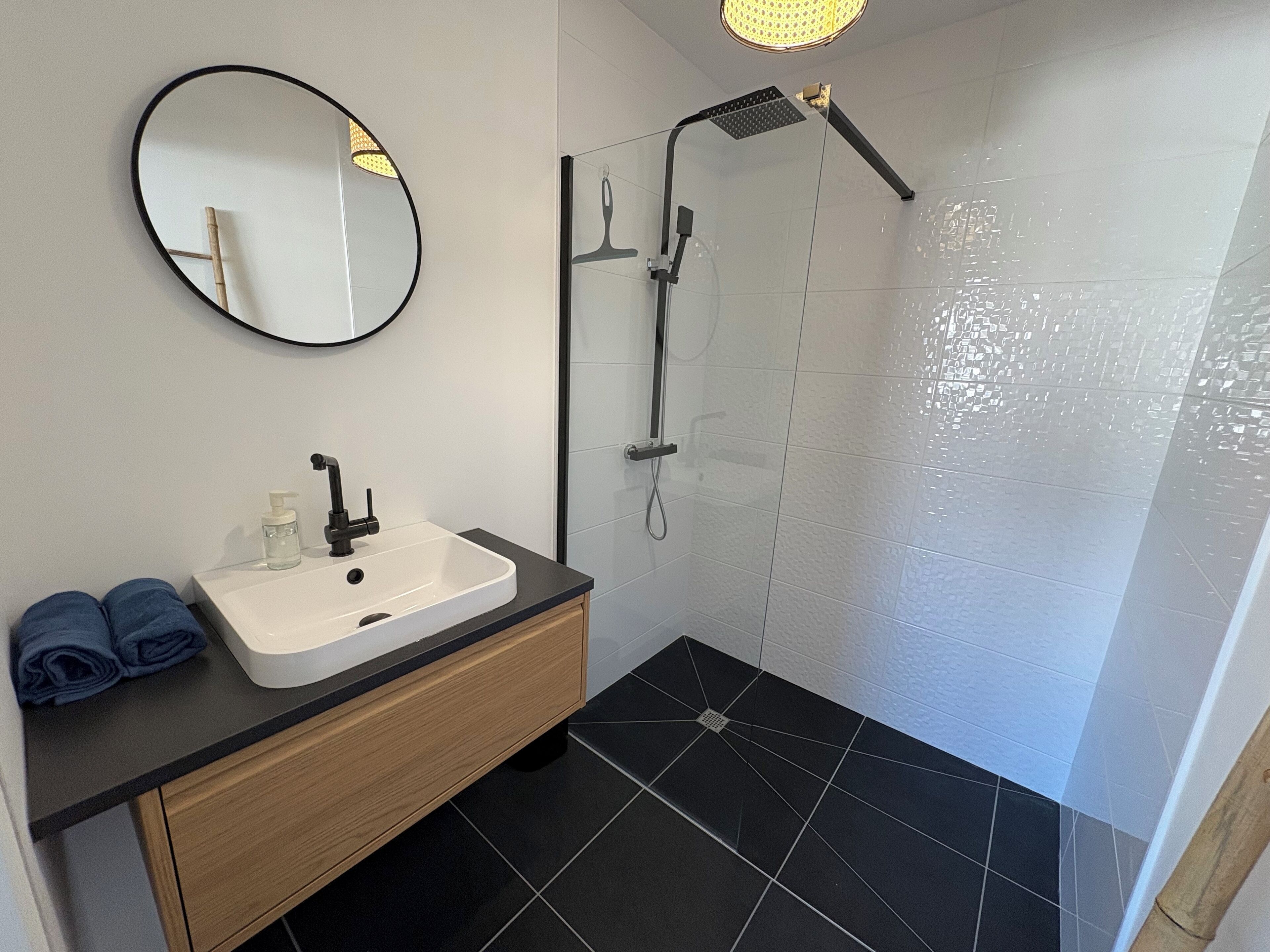 A modern bathroom with a white sink, black countertop, and a wooden cabinet.