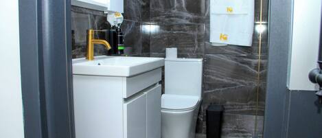 A bathroom with a white sink, gold faucet, and a toilet.