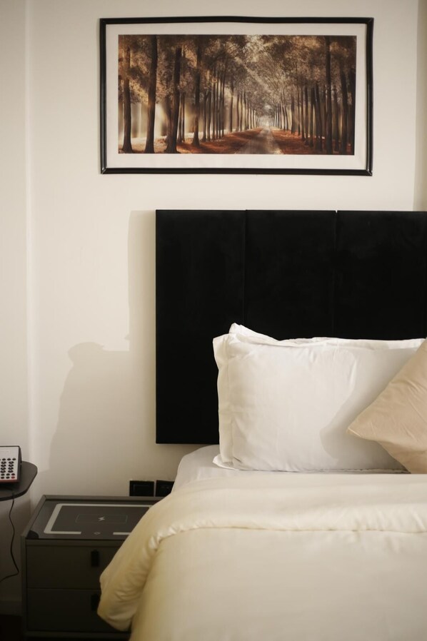 Un dormitorio con cama, mesita de noche y un cuadro enmarcado en la pared.