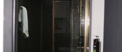 A modern bathroom with a glass-enclosed shower, a white sink, and a toilet.