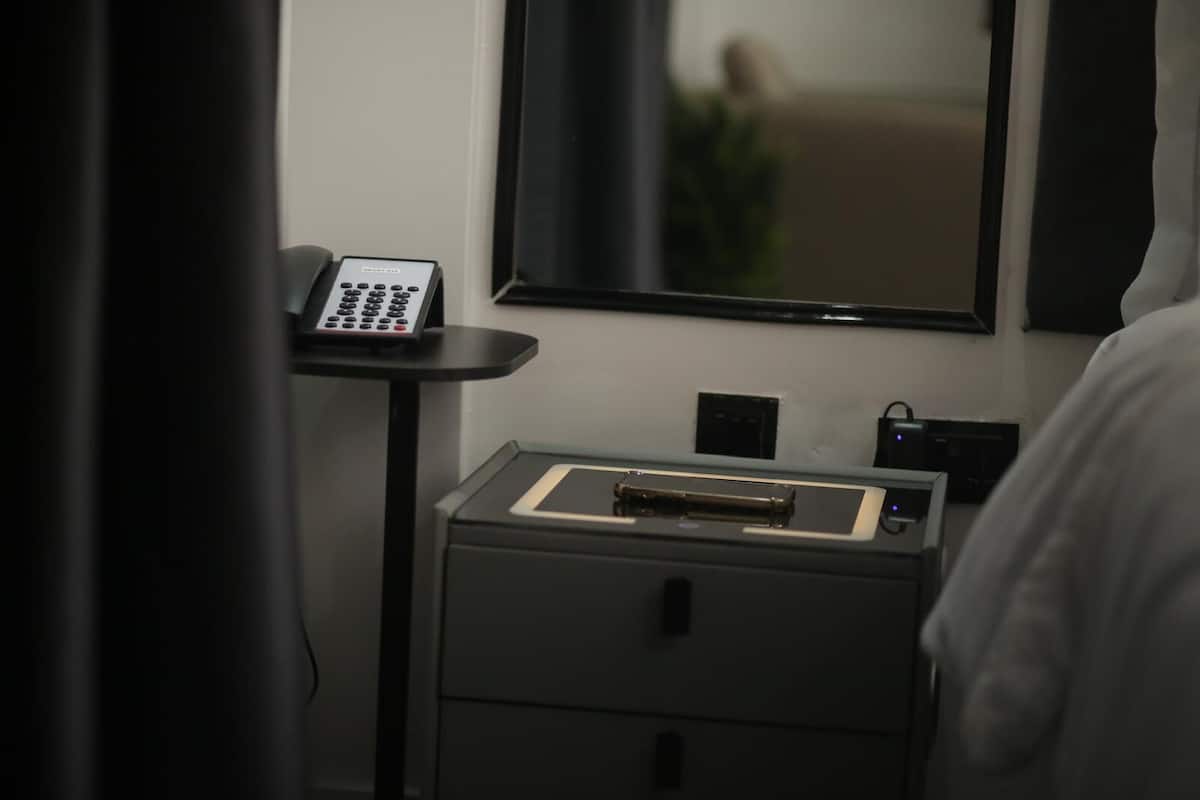 A hotel room with a desk, a telephone, a small table with a tray, and a mirror on the wall.