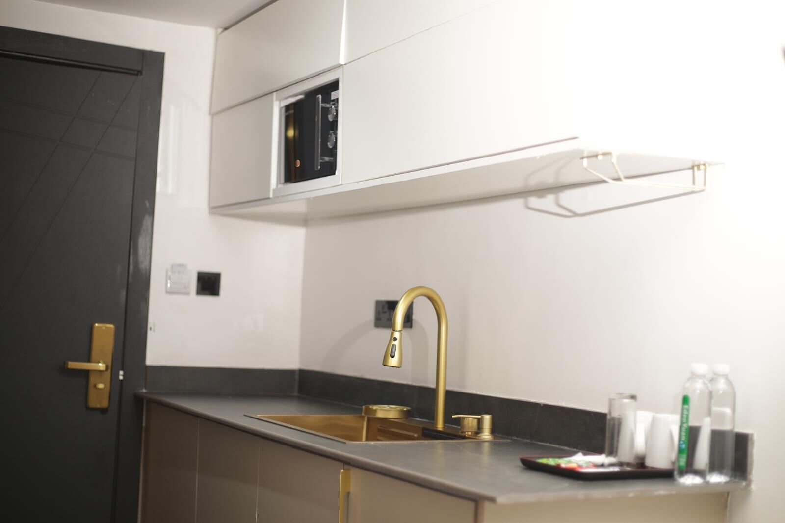 A modern kitchen with a gold faucet, a built-in microwave, and a small countertop with a sink.