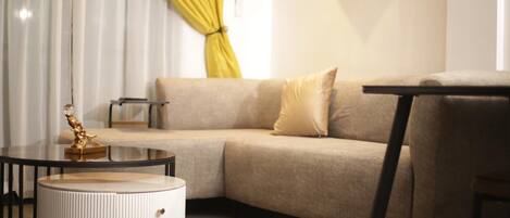 A modern living room with a beige sectional sofa, a round coffee table, and a small side table.