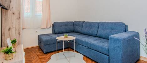A modern living room with a blue sectional sofa, a small round table, and a white rug.