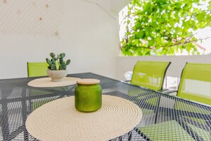 A table with a woven placemat, a green ceramic pot with a plant, and a small ceramic container. - Apartment Pisacic (Vir)