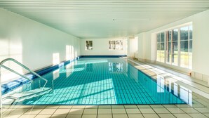 Ein Innenpool mit hellblauen Fliesen, einem Fliesenboden und einer Decke mit horizontalen Linien.