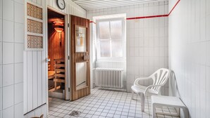 Ein Zimmer mit Holztür, weißem Heizkörper, weißem Stuhl und einem Fenster mit Ausblick.