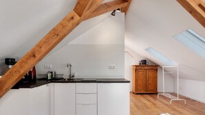 A kitchen with white cabinets, a black countertop, and wooden beams. There is a skylight and a metal drying rack. - Studio 'Bergwiese' with Mountain View, Private Terrace and Private Garden (Lauterbach)