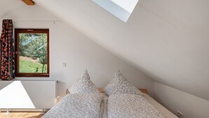 A bedroom with a skylight, a window with a view of greenery, and a bed with floral bedding. - Studio 'Bergwiese' with Mountain View, Private Terrace and Private Garden (Lauterbach)