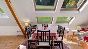 A dining area with a table and chairs, a lamp, and a view through skylights. - Studio 'Bergwiese' with Mountain View, Private Terrace and Private Garden (Lauterbach)