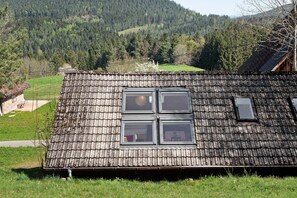 Un edificio rústico de madera con techo inclinado, cuatro ventanas y un pequeño tragaluz.