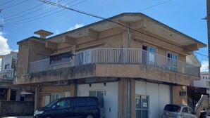 A multi-story building with a balcony, a garage, and a parked car. - coco stay ishigaki (Ishigaki)