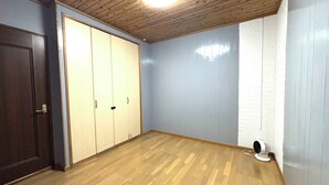 A room with wooden flooring, a ceiling fan, a wardrobe, and a door. - coco stay ishigaki (Ishigaki)