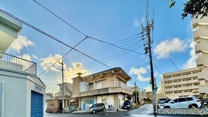 A street view with buildings, a blue garage door, and parked cars. - coco stay ishigaki (Ishigaki)