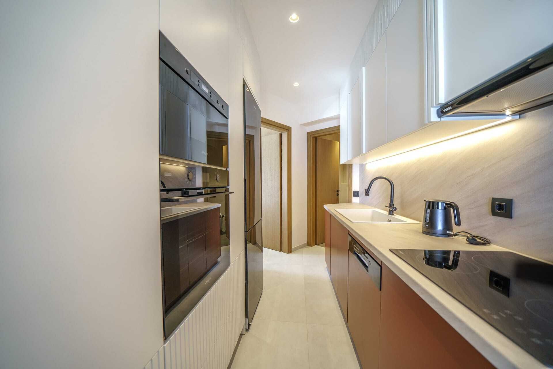 Una cucina moderna con elettrodomestici integrati, un lavello e un bollitore.