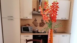 Uma mesa de jantar com um prato laranja decorativo, um vaso com flores vermelhas e uma luminária pendente laranja.