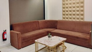 Ein modernes Wohnzimmer mit einem braunen Ecksofa, einem Marmortisch, einem Deckenventilator und einer Wandverkleidung.