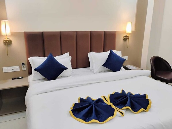 A hotel room with a large bed, two bedside lamps, a nightstand, and a chair.