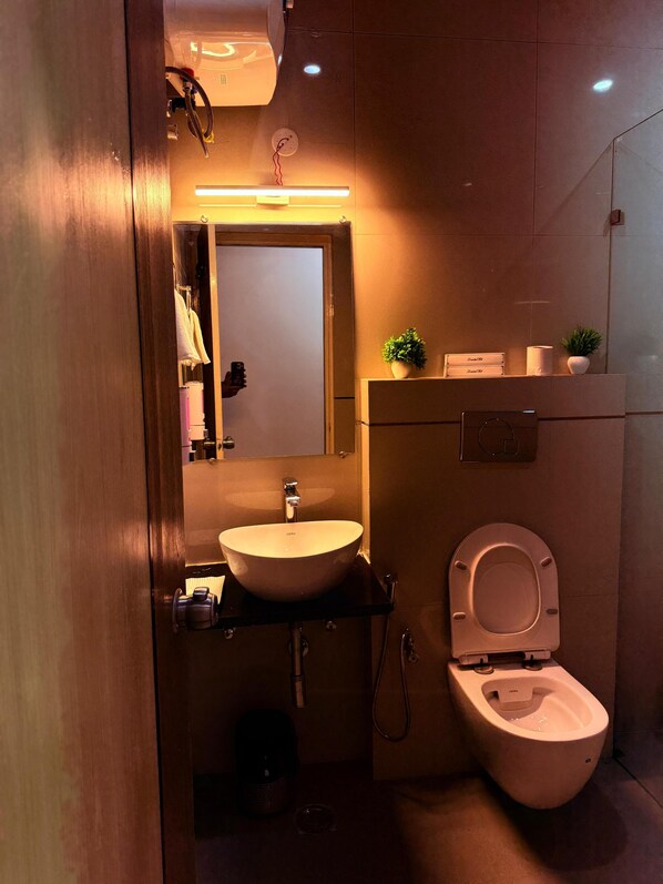 A compact bathroom with a sink, toilet, and a mirror. - Hotel Vasudevay Inn (Haridwar)