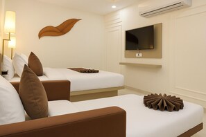 A hotel room with two beds, a TV mounted on the wall, and a modern lamp. - Hotel Vasudevay Inn (Haridwar)