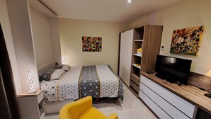 A bedroom with a bed, a TV, a desk, and a chair. - Studio Cécilia (Aix-les-Bains)