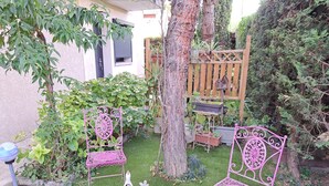A small patio with two pink metal chairs, a white table, and a bird feeder. - Studio Cécilia (Aix-les-Bains)