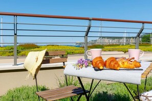 Een tafel met croissants, een kopje en een bank met een gevlochten zitting.