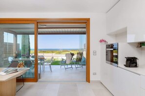 Eine moderne Küche mit Glastür und Zugang zu einem Balkon mit Gartenmöbeln.