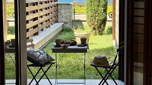 An outdoor patio with a table set for two, a bench, and a view of the sea.