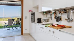 A modern kitchen with white cabinets, a built-in oven, and a view of the outdoors.