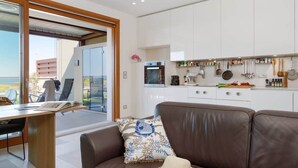 A modern kitchen with white cabinets, a dining area with a table and chairs, and a large window offering a view.