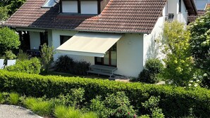 A modern two-story house with a red-tiled roof, a covered porch, and a well-maintained garden.