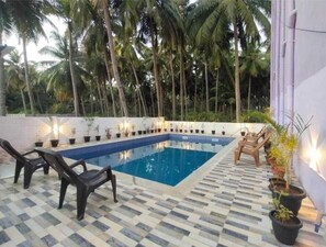 A swimming pool with a checkered floor, surrounded by potted plants and chairs. - AP Heaven Villa (Vanur)