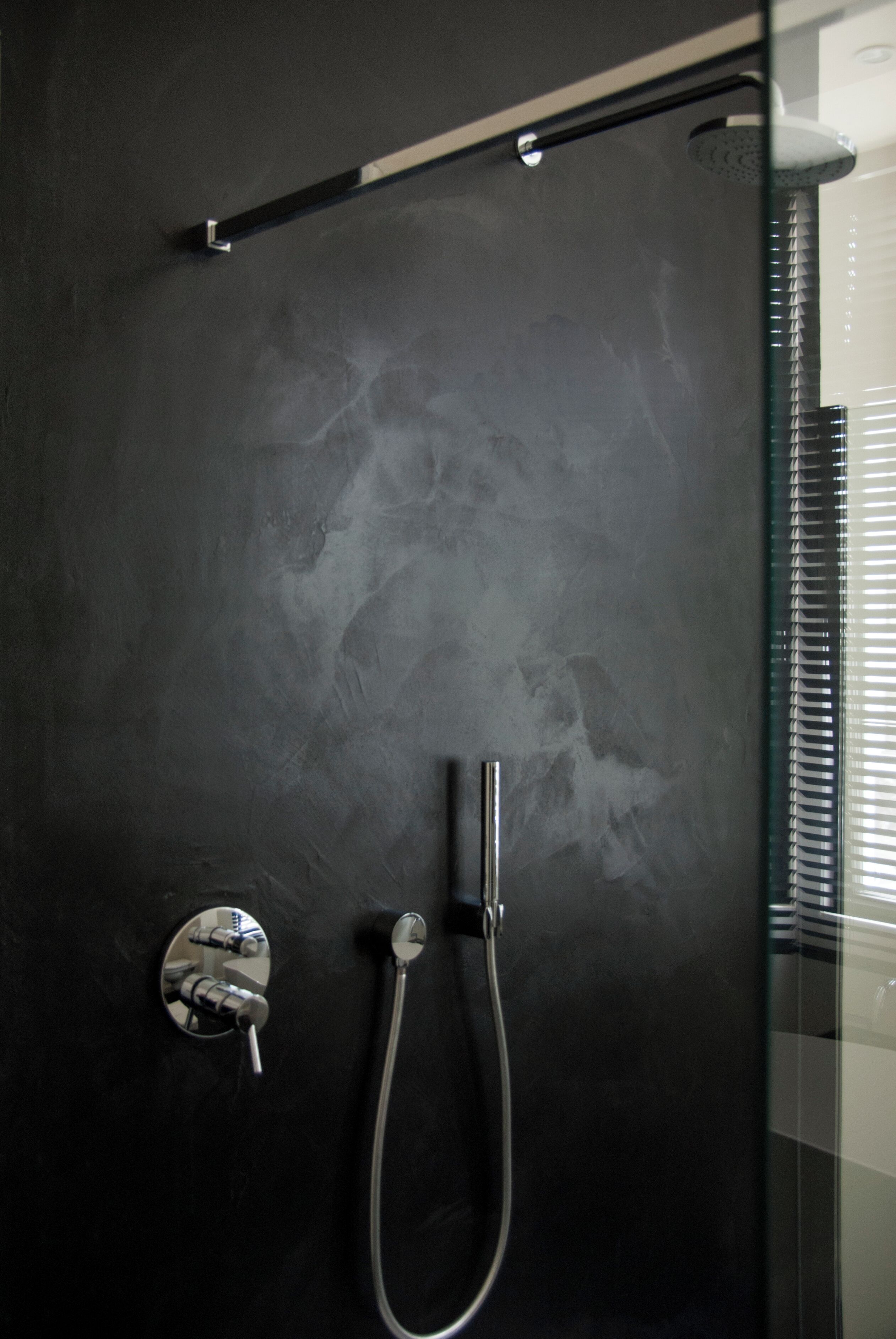 Una ducha moderna con cabina de vidrio, cabezal de ducha de mano y panel de control empotrado.